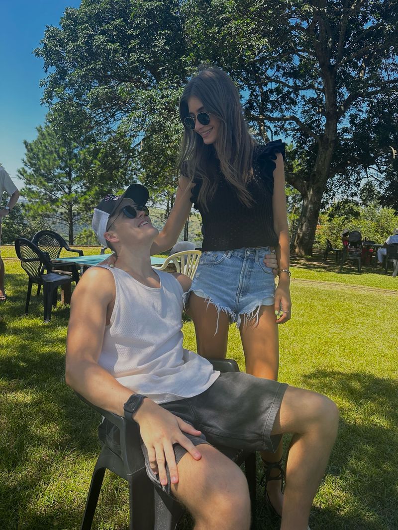 Kyra fixing Dustin's cap on a sunny lawn